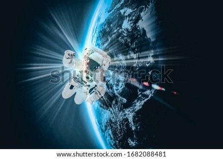 Astronaut in outer space over of the Earth with sun light. City lights on planet. Elements of this image furnished by NASA.