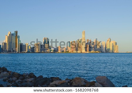 View of the city behind the Pacific Ocean from the rocky shore.