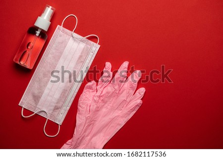 Virus protection. Medical surgical mask, sanitizer gel and lab gloves on red background. Risk Coronavirus disease COVID-19 pandemic concept. Medical respiratory bandage face