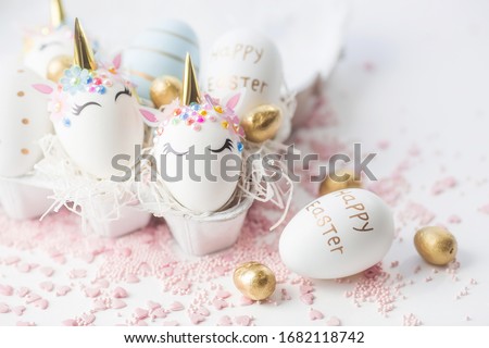 Banner. Easter eggs in the form of a unicorn, and with a gold pattern on a white background. Flat lay. Copy space for text. 