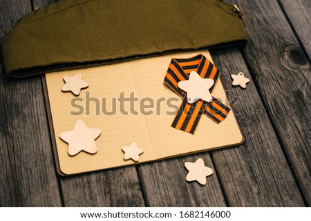 May 9. VICTORY DAY. Ribbon, notebook, wooden stars.  Wooden background. Victory, memory, the concept of veterans.
