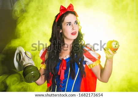 Woman dressed as a character from a fairy tale holds Radioactive atomic nuclear ionizing radiation danger warning symbol on apple. Nuclear and radiation measurement concept.