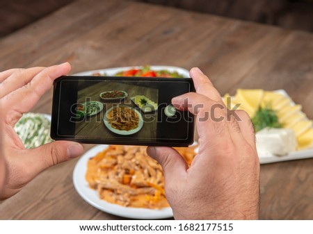 Food blogger using smartphone taking photo .Mans hands make phone photography of  traditional meals. lunch or dinner.Beef stroganoff. For social media, blogging. Top view mobile phone.