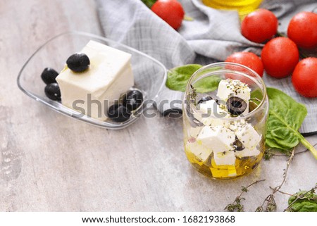 Tasty feta cheese with olives, oil and spices on grey background