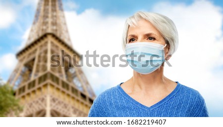 health, safety and pandemic concept - portrait of senior woman wearing protective medical mask for protection from virus over eiffel tower in paris, france background