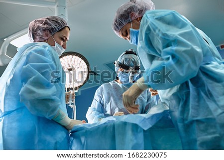 In the hospital operating room. An international team of professional surgeons and assistants works in a modern operating room. Professional doctors celebrate successfully saved lives.