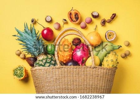 Exotic fruits in straw summer bag. Tropical pineapple, banana, pitahaya, kiwano, african horned melon, tamarillo fruit, granadilla, salak, snake fruit, maracuya, rambutan, lychee, longan, tamarind Royalty-Free Stock Photo #1682238967