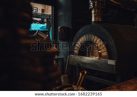 Dark brick pizza oven with fire in restaurant 