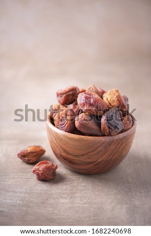 Homemade dried apricots in wooden bowl on wood textured background. Copy space. Superfood, vegan, vegetarian food concept. Macro of dried apricot, selective focus. Healthy snack