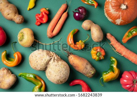 Trendy ugly organic vegetables. Assortment of fresh eggplant, onion, carrot, zucchini, potatoes, pumpkin, pepper in craft paper bag over green background. Top view. Cooking ugly food concept. Non gmo Royalty-Free Stock Photo #1682243839