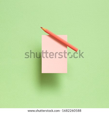 Pink memo note pad with pink colored pencil on green background