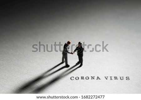 Miniature men hand shaking with word coronavirus 