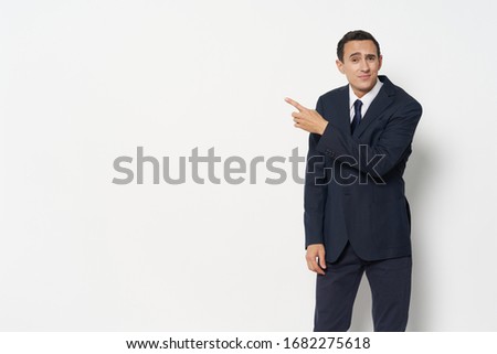 A man in a dark suit points with his finger to the side