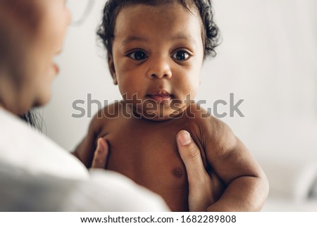 Portrait of enjoy happy love family african american mother playing with adorable little african american baby.Mom touching with cute son moments good time in a white bedroom.Love of black family 