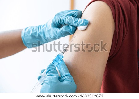 Doctor making injection vaccination patient to prevent pandemic of the disease, flu or influenza virus in clinic.