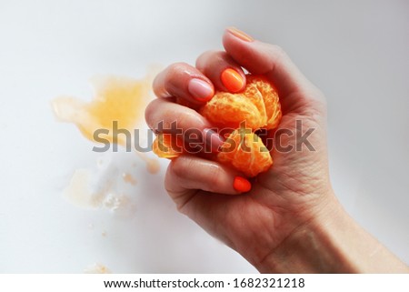 female hand with bright manicure holds a mandarin