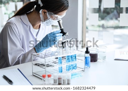 Scientist or medical in lab coat working in biotechnological laboratory, Microscope equipment for research with mixing reagents in glass flask in clinical laboratory. Royalty-Free Stock Photo #1682324479