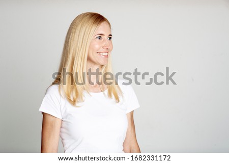 Close up portrait with copy space of half turned attractive pretty mature woman looking to the side over gray wall