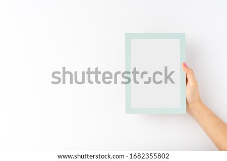 Woman’s hands holding empty photo frame on white background with copyspace. Mock up