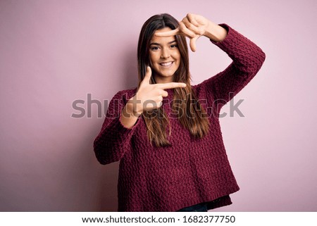 Young beautiful girl wearing casual sweater over isolated pink background smiling making frame with hands and fingers with happy face. Creativity and photography concept.