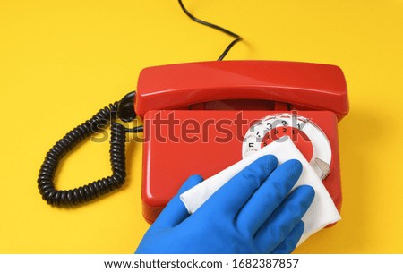 Worker's hand wipes dust and dirt on a landline phone. A maid or housewife takes care of the house. General, regular cleaning. The concept of a commercial cleaning company.Virus disinfection.