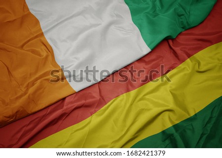 waving colorful flag of bolivia and national flag of cote divoire. macro