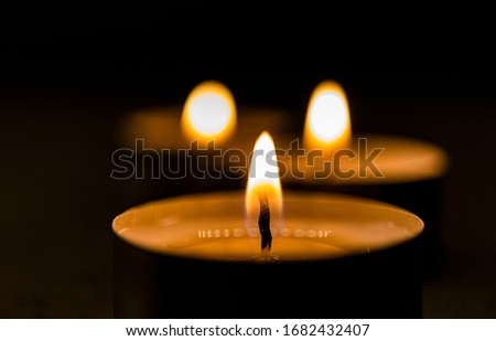 Candle with flames in the foreground with other candles in the background