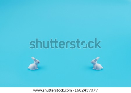 Small white rabbits on blue background. Happy Easter holiday concept. Greeting card. Concept of minimalism. Copy space for your text. 