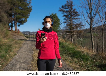 woman outdoor listening to the music with headphones and mobile 