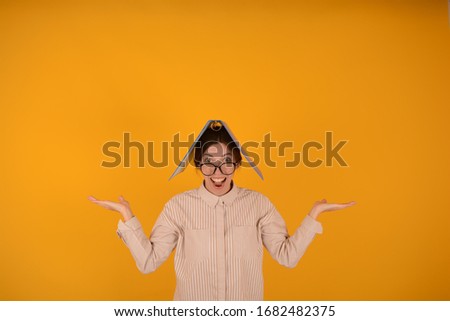 Joyful cheerful business woman in glasses holds a folder on her head in her hands. Free space for copying on a yellow background