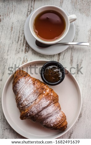 croissant with jam and tea on a white wooden background. background texture screensaver. photo with space for caption