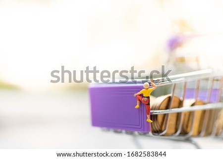 Miniature people : Women are climbing on shopping cart. Image use for retail business concept, shopping concept