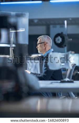 Shot of Industrial Engineer Working in Research Laboratory / Development Center, Using Computer. He is Working on New Efficient Engine Concept Design.