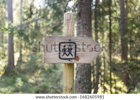Wooden hiking trail signs arrows with hiker figures pointing in direction on a wooden sign post in woods