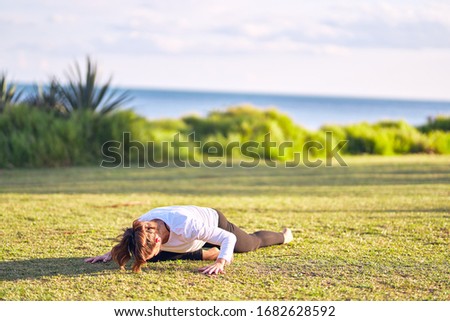 Young beautiful sportwoman practicing yoga. Coach teaching upward-facing dog pose at park