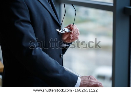 Adult male businessman, teacher, mentor looks out the large window of his office. Work in the office. Development of a new business project