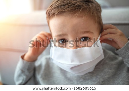 2-3 years old child wearing surgical mask. Little boy trying to stay healthy by wearing a mask to protect him against corona virus covid-19 / 2019-nCov. Boy wearing anti virus mask staying at home
