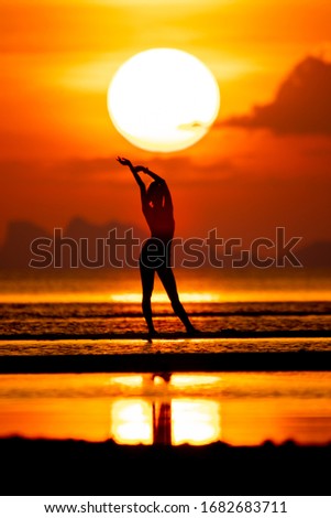 Silhouette of young woman at sunset and big sun.