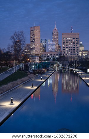 Indianapolis city lights with reflections in the Central Canal at dusk.