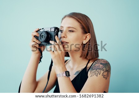 Stylish young girl photographer taking photos on blue background