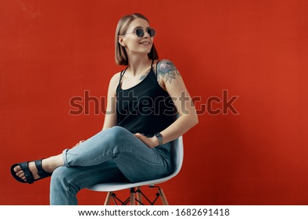 Young girl sitting on a white chair near the red wall. Natural light from the window