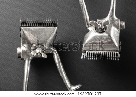 on ablack surface are old barber tools. two vintage manual hair clipper, black monochrome. horizontal orientation.
