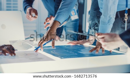 Engineer, Scientists and Developers Gathered Around Illuminated Conference Table in Technology Research Center, Talking, Finding Solution and Analysing Industrial Engine Design. Close-up Hands Shot Royalty-Free Stock Photo #1682713576