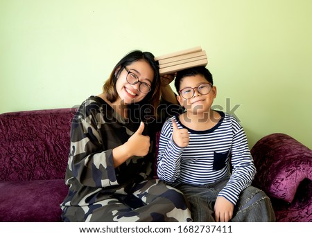 Asian mother and son sitting and smiling in living room. Education concept, family relationship, positive attitude. Thumb up together. Homeschool, social distancing, Safety in the COVID19 period.