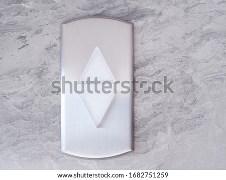 Elevator with lift silver button triangle up and down on marble pattern wall.