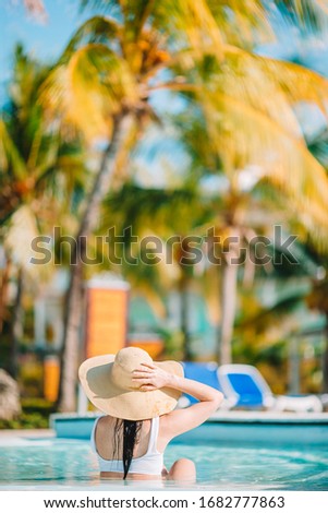 Beautiful young woman relaxing in swimming pool. Girl in bikini in outdoor pool at luxury hotel