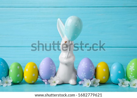 Easter bunny and painted eggs on light blue wooden background