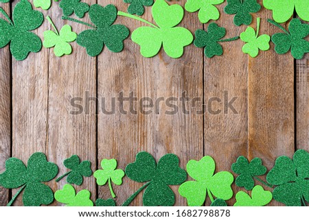 Frame made of clover leaves on wooden table, flat lay with space for text. St. Patrick's Day celebration