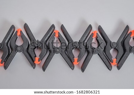 Black and orange construction clamps on a white background. Set of medium plastic clips. Clamping tools for carpentry. Hand tools for needlework. Clamping equipment.