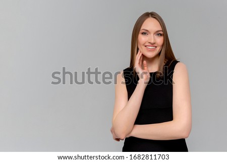 Happy that everything is okay. Portrait of charming friendly caucasian girl with braces smiling cheerfully while standing against monochromatic background, listening order or talking to coworker